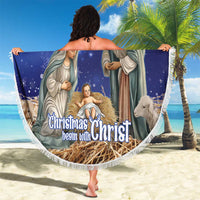 Round blue Christmas nativity beach blanket held up outdoors, white fringe border