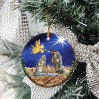 Blue ceramic round Christmas ornament with nativity scene, hanging on evergreen branches.