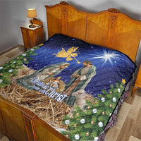 Blue Christmas quilt laid on bed showing nativity artwork, angel icon and pine branches