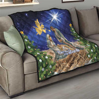 Blue Christmas quilt draped over sofa showing nativity figures and golden angel symbol