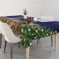 Blue Christmas tablecloth draped on dining table with pine branches and round ornaments