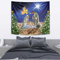 Blue Christmas tapestry showing baby in manger, parents, angel above, and evergreen borders