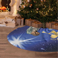 Blue Christmas tree skirt laid around tree base, nativity print with angel and figures