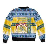 Unisex blue bomber jacket with yellow back graphic featuring coat-of-arms and festive motifs