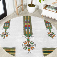 Round white rug with central cross and colorful tiled pattern, green orange accents
