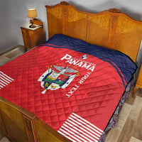 Red and navy quilt blanket on bed with Panama crest, “Panama” text, and striped hem.