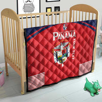 Red and navy Panama quilt blanket on a wooden crib, with crest emblem and stripe corners.