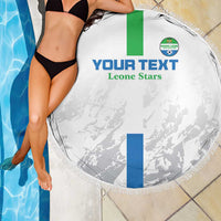 White round beach blanket with fringe, green/blue stripes and Leone Stars print, draped