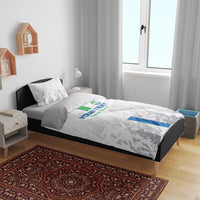 White bedding set on bed with grey patterned duvet, blue/green stripe detail and pillows