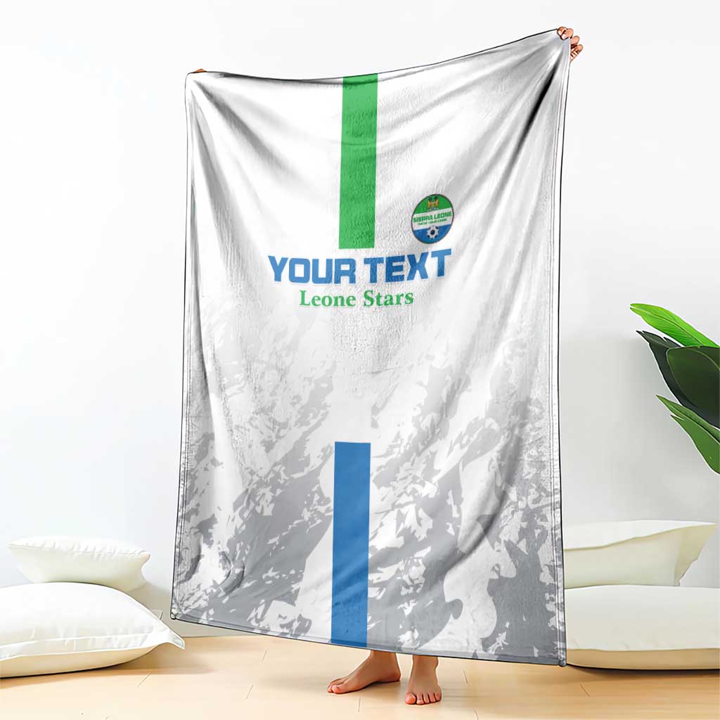 White and gray football blanket draped with green stripe, blue panel, and Leone Stars crest