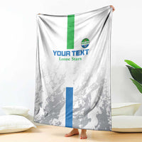 White and gray football blanket draped with green stripe, blue panel, and Leone Stars crest