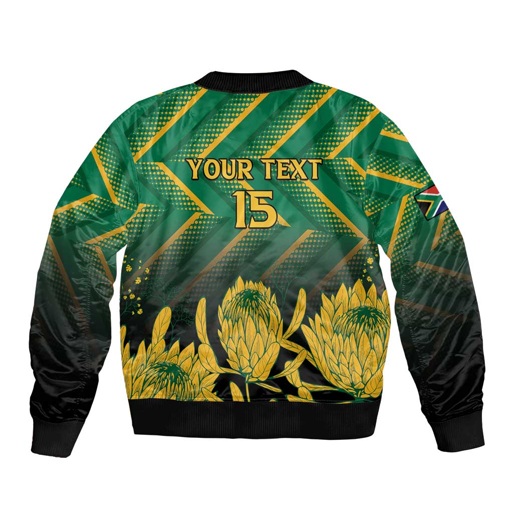 Green zip-up bomber jacket with black sleeves, "YOUR TEXT" 15 back print and gold protea graphic