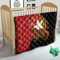 Red and black baby quilt in a crib with quilted diamonds and golden crocodile 40th anniversary logo