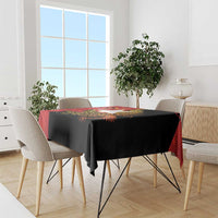 Black tablecloth with red border and colorful gold crocodile-themed design on a dining table
