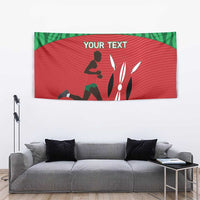 Red and green Kenyan runner tapestry with 'YOUR TEXT' and silhouette art, above sofa