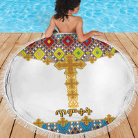 Round white beach blanket with colorful cross tile design and fringed edge