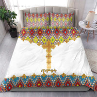 White duvet cover bedding set with gold cross emblem and colorful geometric border; two pillows.