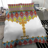 White bedding set with gold cross center and colorful diamond tile pattern border; two pillows.