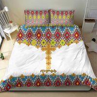 White bedding set featuring gold cross design and colorful geometric tile stripe; two pillows.