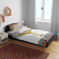 White bedding set on bed with gold cross design and colorful geometric tile accent; two pillows.
