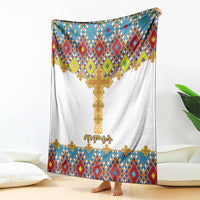 White blanket with gold cross centerpiece and blue, red, green geometric border