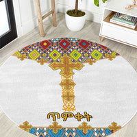 Round white rug with colorful Ethiopian-style cross and diamond tile pattern border