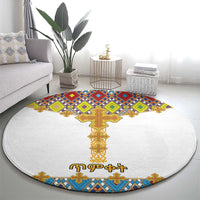 Round white rug with multicolor geometric tile design and a large gold cross emblem