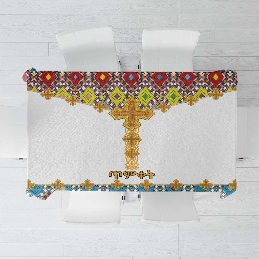 White tablecloth with colorful cross and geometric tile pattern, gold fringe edge