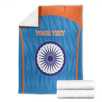 Folded blue cricket blanket with orange border, Indian emblem circle and 'YOUR TEXT'.