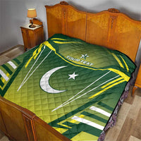 Green quilt on bed with yellow-and-white Pakistan flag graphic, crescent and star, "YOUR TEXT"