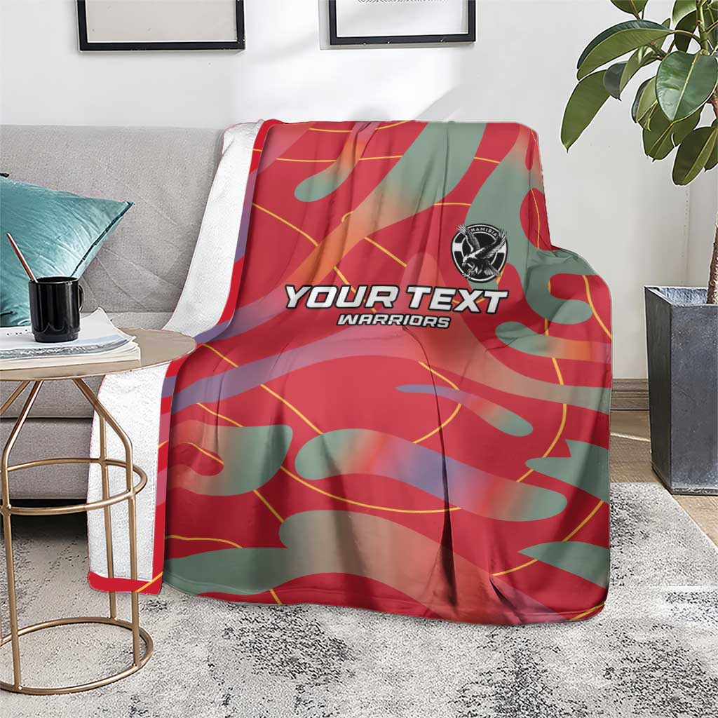 Red and teal football blanket draped over couch with YOUR TEXT WARRIORS print and emblem