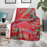Red and teal football blanket draped over couch with YOUR TEXT WARRIORS print and emblem