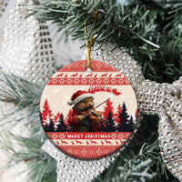 Round red-and-white ceramic Christmas ornament with pine marten playing violin on a silver tinsel tree