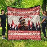 Red Christmas quilt displayed outdoors with pine marten playing violin, pine trees, 'Merry Christmas'.