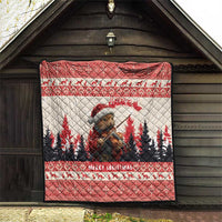 Red Christmas quilt hung on a wooden wall, featuring pine marten playing violin and pine trees.