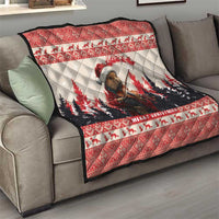 Red Christmas quilt spread on a gray sofa, with pine marten playing violin and 'Merry Christmas'.