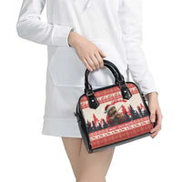 Red and black Christmas shoulder handbag held by a person, showing front zipper and handles