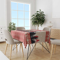 Red patterned Christmas tablecloth draped over dining table with chairs