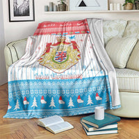 Christmas blanket with coat of arms, red top and blue pine border, draped on sofa