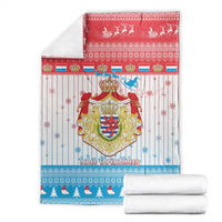 Christmas blanket with Luxembourg crest graphic, with folded white towels underneath