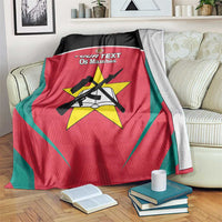 Red football blanket with teal edge and crest emblem, draped over bed on a striped mattress