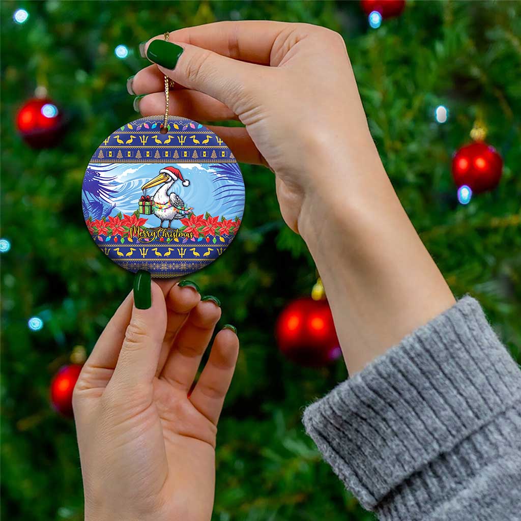 Ceramic Christmas ornament, round blue pelican with poinsettias; held on gold hanging cord
