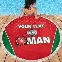 Red Oman beach blanket with green borders and white fringe, shown on wooden deck