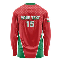 Red long-sleeve cricket shirt with green side panels, flag badge sleeve, back number 15