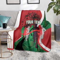 Athletics Kenya blanket on gray sofa, red-white-green runners graphic with 'YOUR TEXT'.