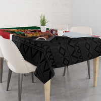 Kenya tablecloth with black geometric weave and diagonal red/green flag border, shield center.