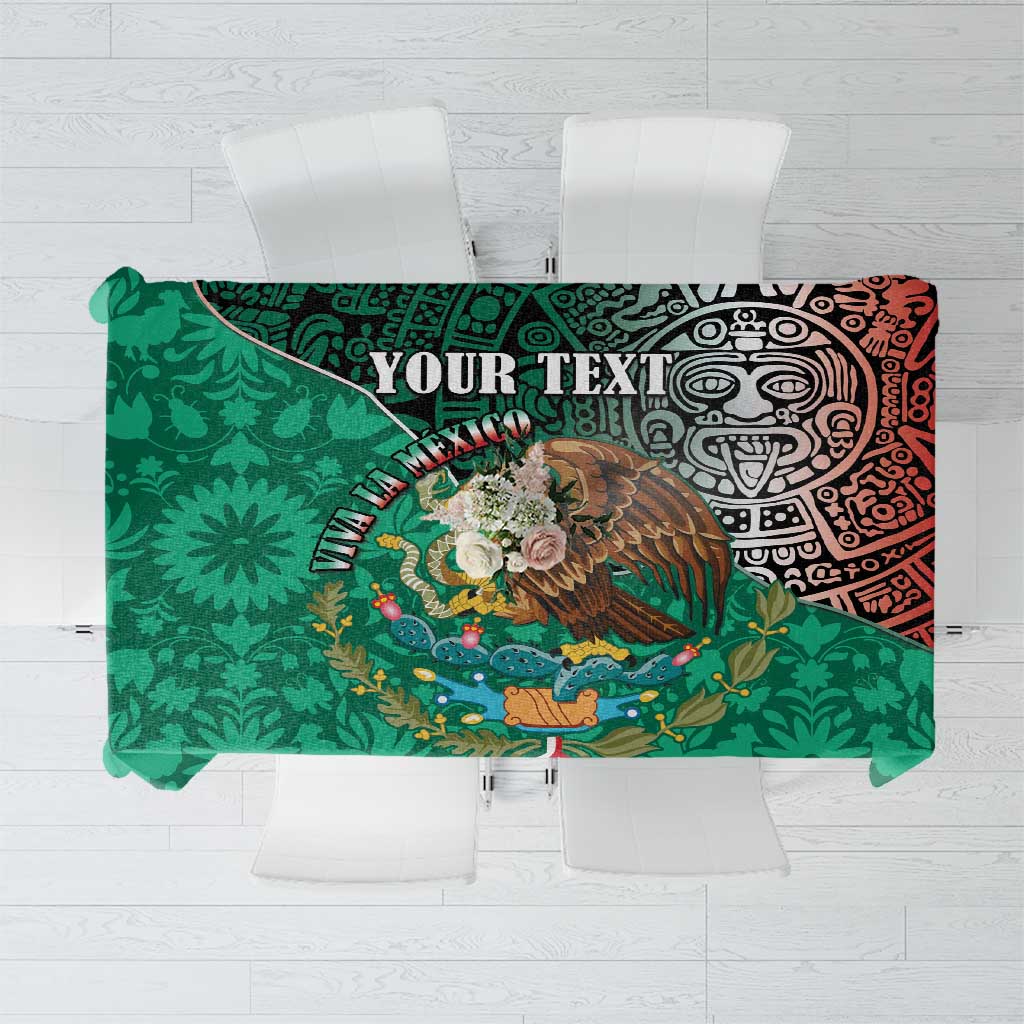 Green tablecloth featuring central eagle graphic and red Aztec-style design, flat view