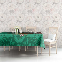 Green tablecloth with dense leaf print and red Aztec border, on dining table
