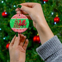 Green round ceramic ornament with red Welsh dragon, held on a gold string.
