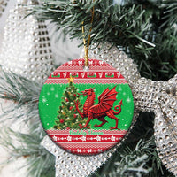 Green round ceramic Welsh dragon Christmas ornament hanging from a tree branch.